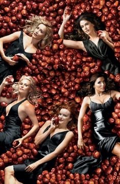 three women in black dresses are surrounded by apples