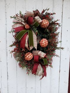 a christmas wreath hanging on the side of a white wooden door with red and green decorations