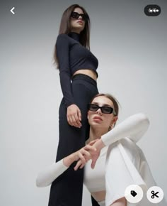 two women standing next to each other in front of a white background and one woman wearing sunglasses