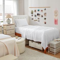 a bedroom with white linens and pictures on the wall above the bed, along with storage drawers