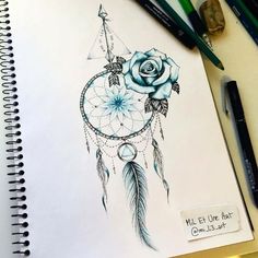 a drawing of a dream catcher with roses and feathers on it's side, surrounded by markers