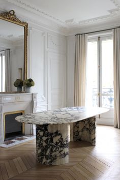 an elegant dining table in the middle of a living room with fireplace and large mirror