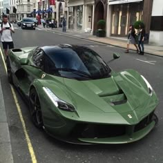 a green sports car is parked on the side of the street in front of people