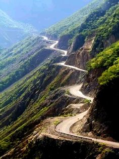 a winding road in the mountains with trees on both sides