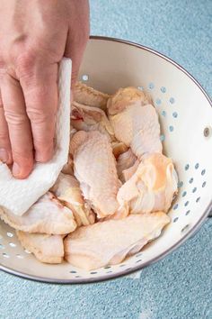 a person is cleaning chicken in a colander