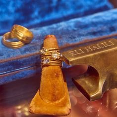 two gold wedding rings sitting on top of a blue velvet covered box next to an old hammer