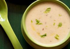 a green bowl filled with soup next to a spoon