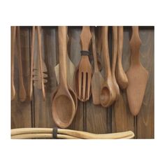 spoons and spatulas are hanging on the wall with wooden utensils