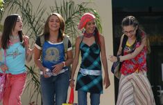 four girls are walking down the street together