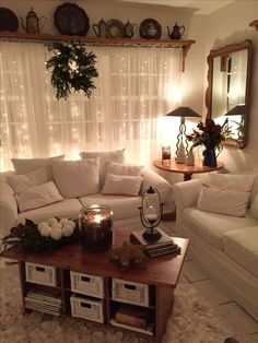 a living room filled with white furniture and christmas lights on the window sill,