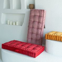 two different colored pillows sitting on top of each other in front of white shelves with candles