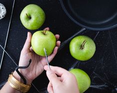 a person cutting an apple with a pair of scissors and some other items on the table