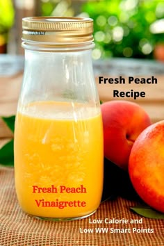 a glass jar filled with liquid next to two peaches