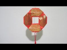 a red and gold ornament hanging on a wall next to a white wall