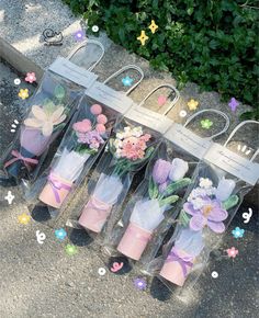 four clear vases with flowers in them sitting on the ground