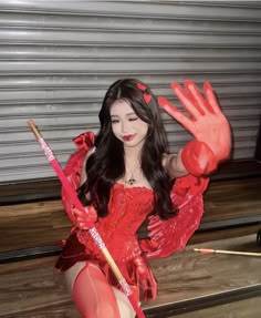 a woman in red is posing with her hands up and holding a broom on the ground