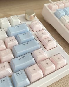 two computer keyboards sitting next to each other on a wooden table, one with blue and pink keys