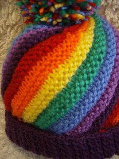 a multicolored crocheted hat laying on top of a white surface with beads