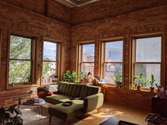 a living room filled with lots of windows next to a couch and coffee table on top of a hard wood floor