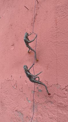 two lizards are climbing up the side of a pink stucco wall with wires attached to it