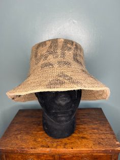 *Handmade individual bucket/sun hat crafted from a coffee bean sack with a lining of pre-loved twill cotton. *Size: Medium - Circumference 24" *This unique hat shows printed/stencilled words Café and Cosecha on the main body of the hat. The outer brim has general stencilled letters relating to the coffee manufacturer, and inner brim is plain. The top has an image of a stylised hook. *Care instructions: machine washable 30 degrees - cool wash - line dry. Iron using a steam setting. The hat is ind Vintage Brown Bucket Hat For Beach, Vintage Brown Bucket Hat For The Beach, Brown Curved Brim Jute Hat, Brown Jute Hat With Curved Brim, Oversized Bucket Hat, Reversible Brown Bucket Hat, Brown Reversible Bucket Hat, Casual Natural Color Bucket Sun Hat, Vintage Brown Bucket Hat One Size