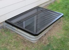 a metal grate sitting in the grass next to a house