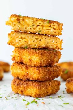 three fried food items stacked on top of each other in front of small bites of bread