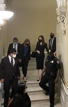 several people in suits and ties walking down the stairs with one person wearing a face mask