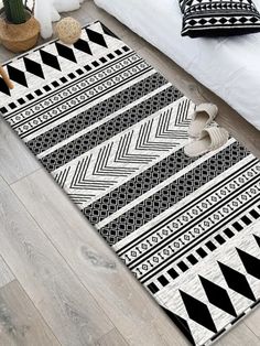 a black and white rug on the floor next to a bed