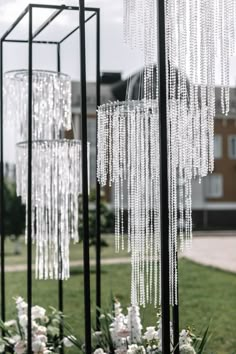 some white flowers and black poles with chains hanging from it's sides in the grass