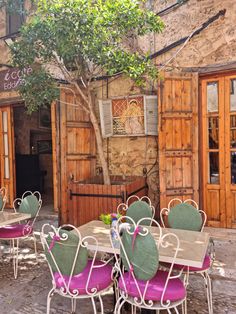 an outdoor dining area with tables and chairs in front of a building that has wooden doors