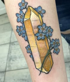 a tattoo with blue flowers and a yellow diamond on the leg that says, i am not sure if it is real or fake