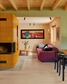 a living room filled with furniture and a fire place next to a dining table on top of a hard wood floor