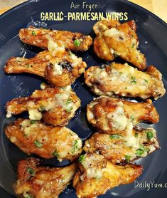 some chicken wings on a blue plate with the words air fryer garlic parmesan chicken wings