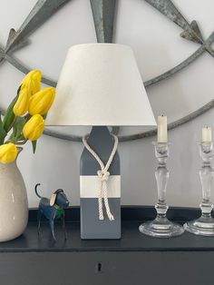 a lamp, vase with yellow tulips and a small figurine on a table