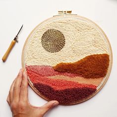 someone is working on an art project with their hand embroiderying the image in red, orange and yellow