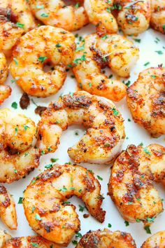 grilled shrimp on a white plate with parsley sprinkled around the edges