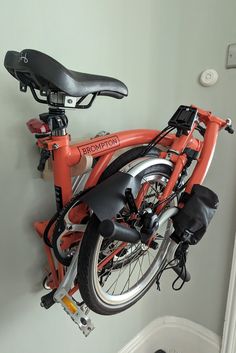 an orange bicycle is hanging on the wall