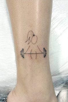 a woman's foot with a tattoo of a dog and barbells on it