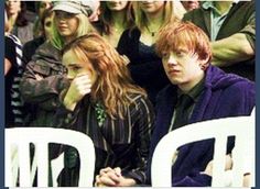 two young people sitting next to each other in front of a group of people watching something