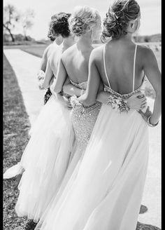 three women in long dresses walking down the street together with their backs to each other