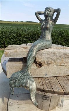 a mermaid statue sitting on top of a wooden bench