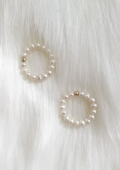 two white pearls are on top of a fur surface and one is in the shape of a circle