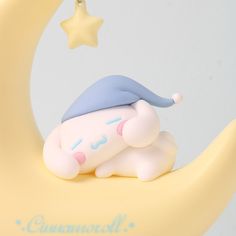 a small toy sleeping on the moon with a star hanging from it's side