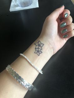 a woman's arm with a flower tattoo on her left wrist and a silver bracelet