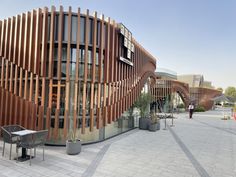 an artisticly designed building with wooden slats on the side and people walking by