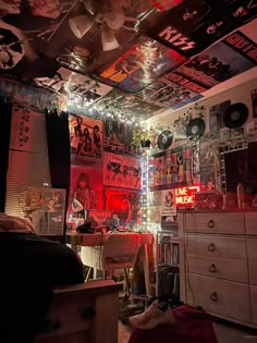 a room filled with lots of posters and lights on the ceiling above it is a bed