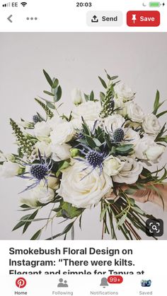 a bouquet of white flowers and greenery is held by someone's hand in front of a white wall