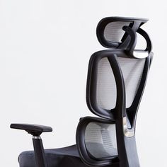 a black office chair with arms and back rests on a white surface against a plain background