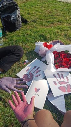 two people sitting in the grass with their hands on roses and cards that say love